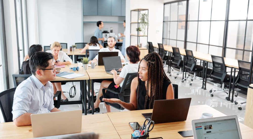 Group of business people sitting at workplace using laptop computers at their work and discussing working moments at modern office